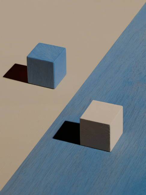 Two wooden cubes resting on blue and tan painted surfaces